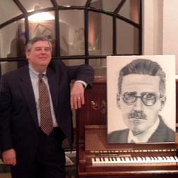 Kevin beside piano and drawing of Joyce